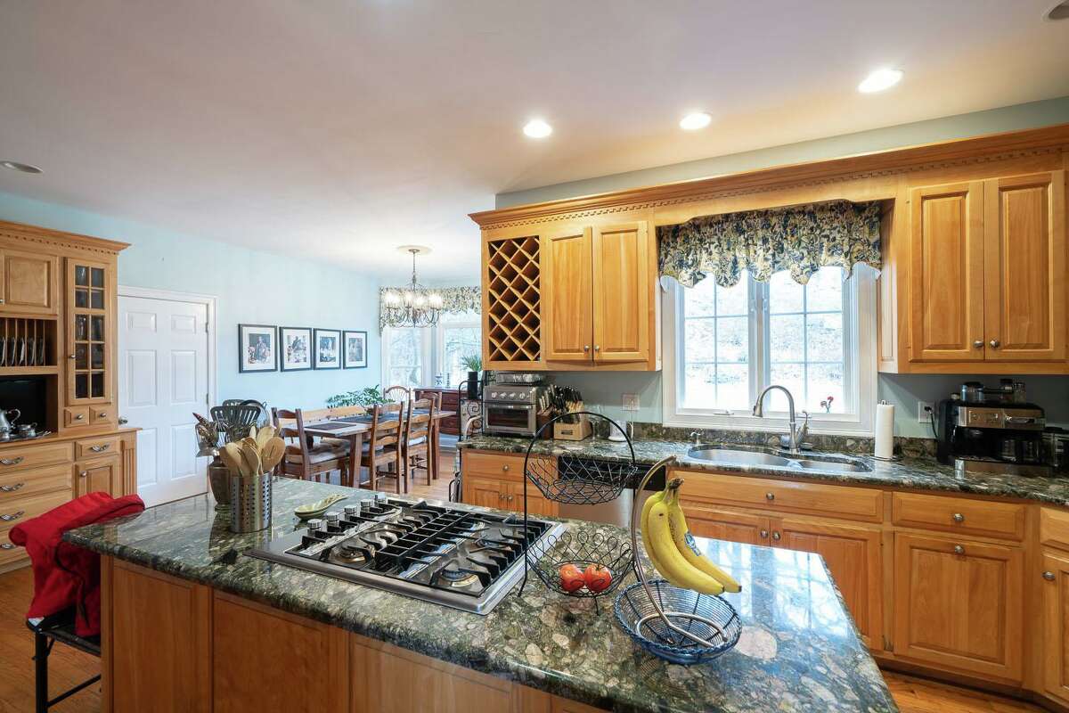 The spacious gourmet eat-in kitchen features a center island, ample granite counters, custom cabinets, a built-in wine rack, a large pantry, and high-end appliances. The front door is flanked by decorative leaded glass sidelights and it opens into a sizable two-story foyer, where there are fluted pilasters at the wide entrance into the formal living room, a ceramic tile floor, and decorative wood appliques on the stringer below the treads of each step on the staircase to the second floor. The house was built in 1998 in such a way that the main level offers a flexible floor plan.