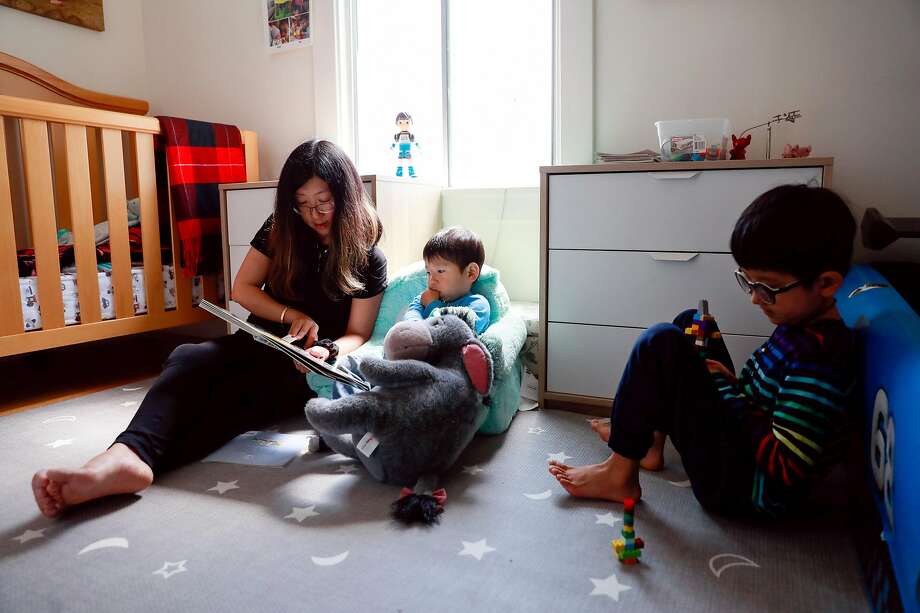 Kai Wang, 7, plays with a toy and listens to his mom Mina Sun as she reads a story to his brother Skyler before she puts him down for a nap. Photo: Gabrielle Lurie / The Chronicle