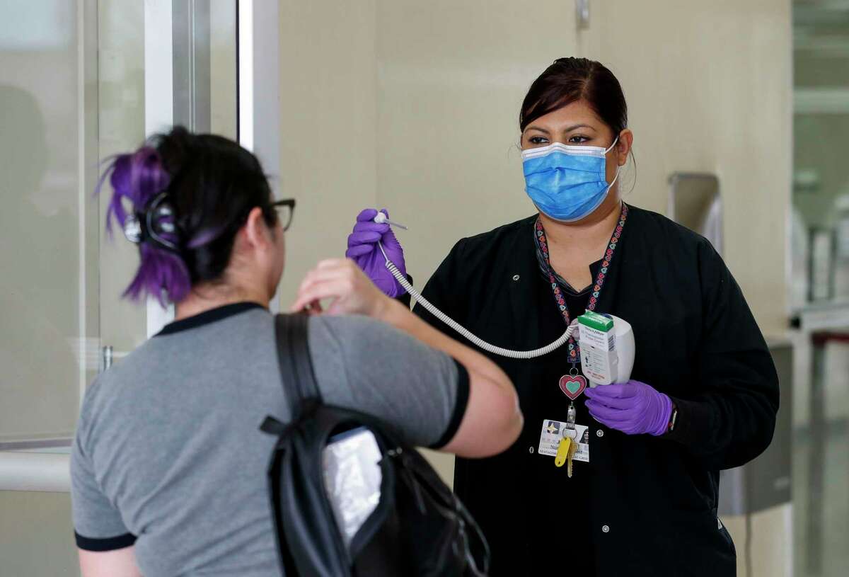 A health professional with the Matagorda Medical Group checks the temperature of a woman entering the Matagorda County Court House in Bay City, Texas, in this March 17, 2020, file photo.