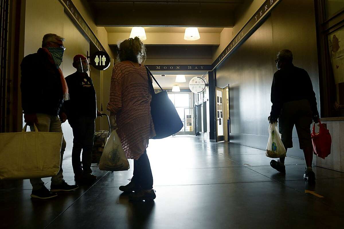 David Shimmon, left to right, and his brother, Steven Shimmon, talk with friend and vendor, Sally Hiebert, in a hallway near a public restroom in the Ferry Building during the Ferry Plaza Farmers Market on Saturday, August 8, 2020, in San Francisco, Calif. Steven Shimmon said that "in the olden days" - the days before the coronavirus pandemic - there used to be lines on market day at the few public restrooms available in the building.