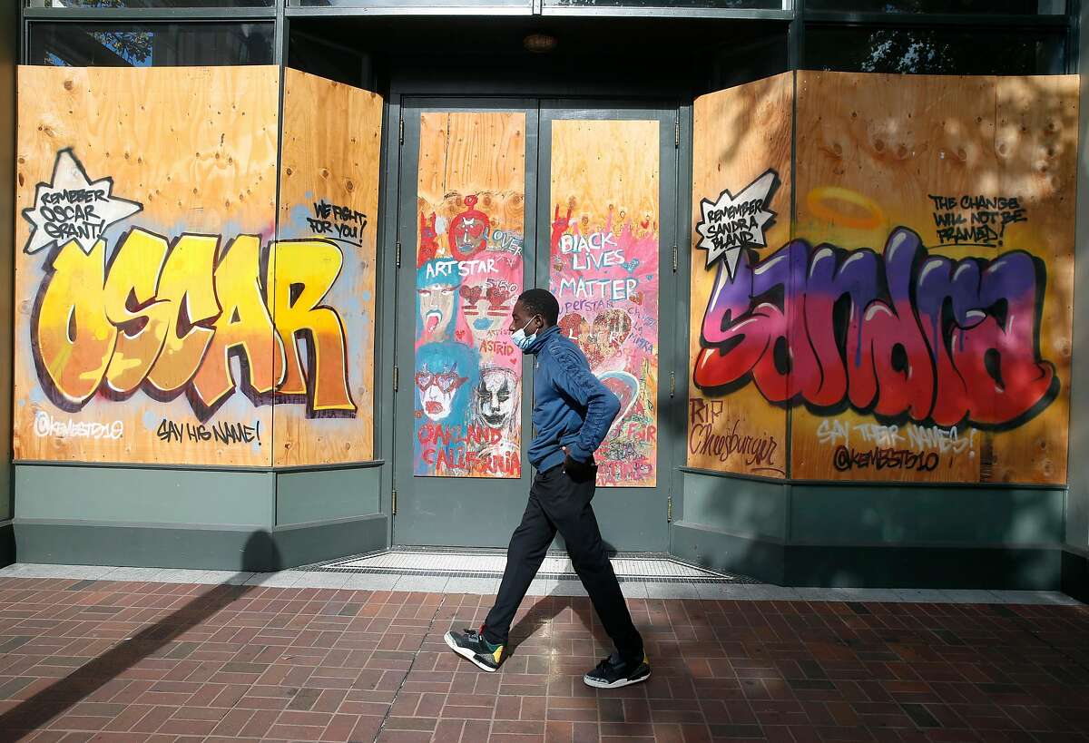 A mural adorns plywood covering the windows of a shuttered Oakland business on Broadway at 9th Street.