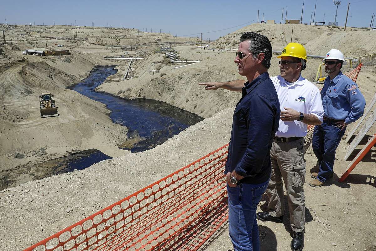 FILE - In this July 24, 2019, file photo, Gov. Gavin Newsom, left, is briefed by Jason Marshall, of the California Department of Conservation, Division of Oil and Gas, center; Billy Lacobie, of Chevron, while touring the Chevron oil field in McKittrick, Calif. Newsom says he is encouraged by Chevron's efforts to clean up what has turned into the state's largest oil spill in decades. California Gov. Newsom moved Wednesday, Sept. 23, 2020 to end issuing new hydraulic fracturing permits by 2024, a delay criticized by many environmental groups but characterized as legally and politically realistic by another. (Irfan Khan/Los Angeles Times via AP, Pool, File)