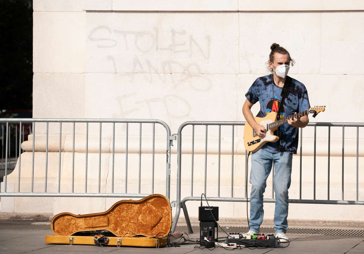 A musician wears a face mask while playing electric guitar in New York City's Washington Square Park.