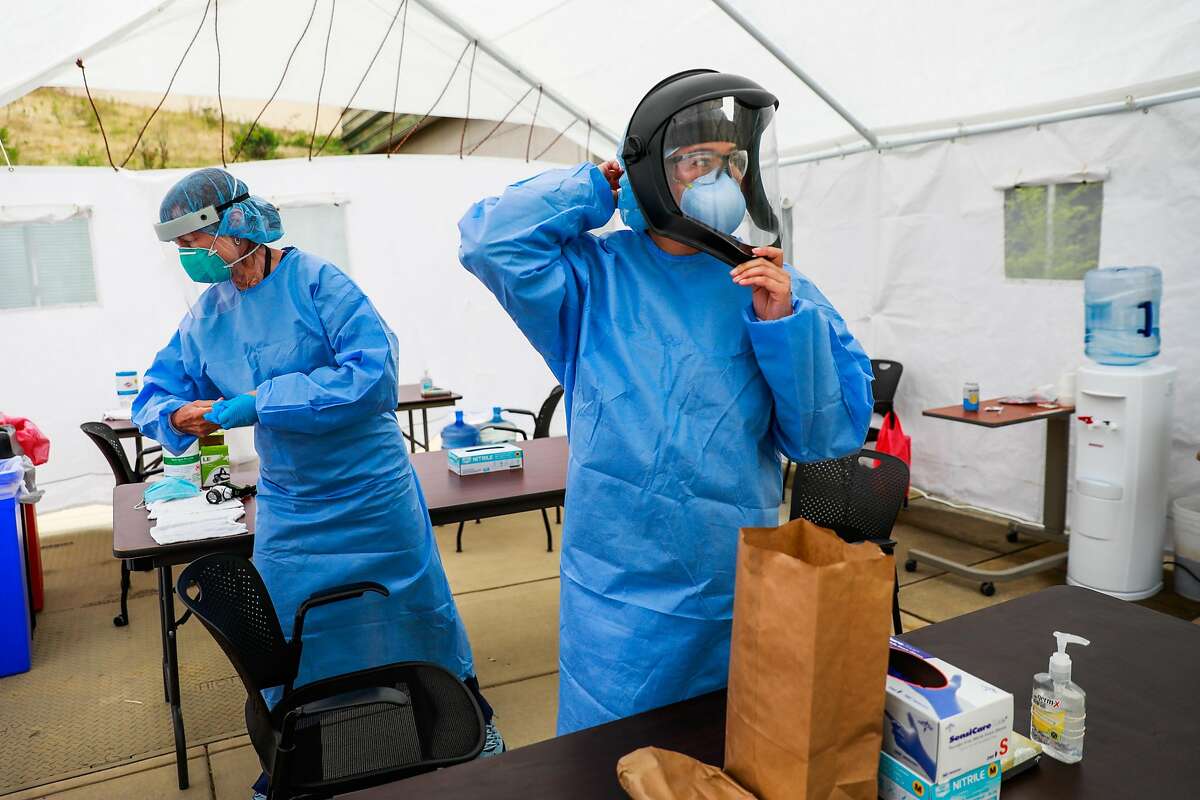 2020年6月25日，星期四，在加利福尼亚州旧金山的拉古纳本田医院，护士罗斯玛丽·麦克劳德(左)和护士波琳·特兰在进行新冠病毒检测之前穿上了个人防护装备。