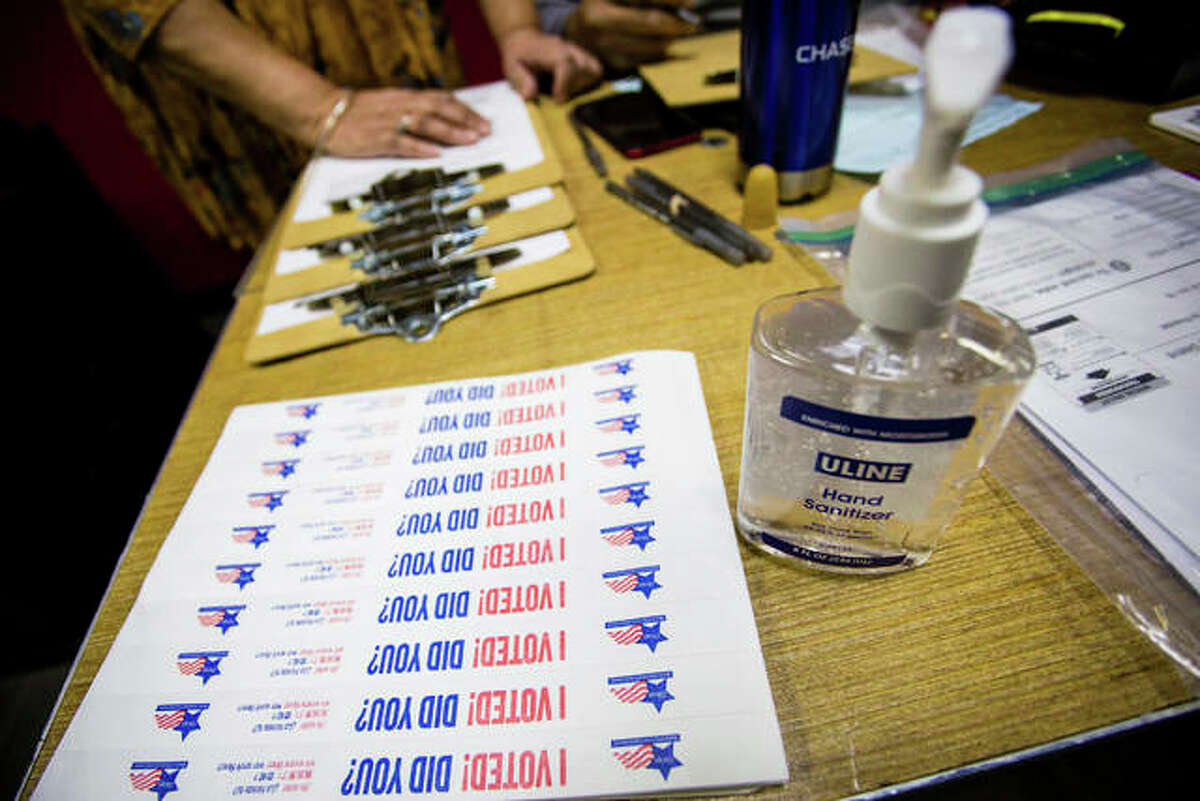 In this March 17 file photo, hand sanitizer and stickers are set up at a polling station in Chicago. Election Day voters, whose numbers have waned in recent years because of expanded options for casting ballots, likely will be reduced even further this year with a surge in vote-by-mail popularity during a pandemic. Ballots to those who applied to vote by mail started going out on Thursday, Sept. 24, to a record 1.82 million voters thus far, according to the Illinois State Board of Elections. Legislation adopted last spring ensured widespread publicity for the practice because of the coronavirus outbreak.