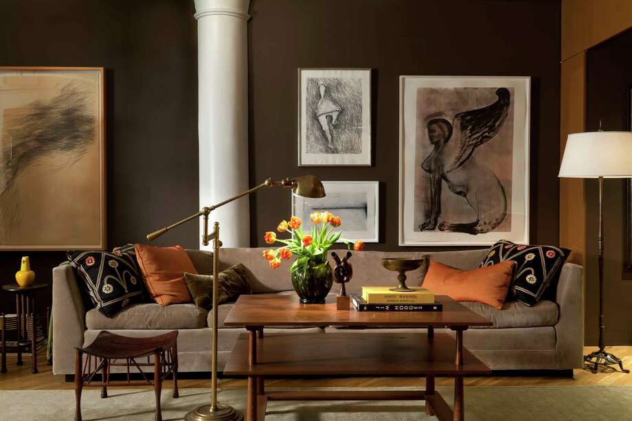 New York-based designer Glenn Gissler painted this New York loft in Benjamin Moore's deep, rich Van Buren Brown, with columns and ceilings in crisp Decorator's White. A long tuxedo-style sofa in milk chocolate-y velvet anchors the space along with tonal modern art. The result is a chic, contemporary yet cozy and eminently livable space. (Gross & Daley/Glenn Gissler via AP) Photo: Gross & Daley / Glenn Gissler