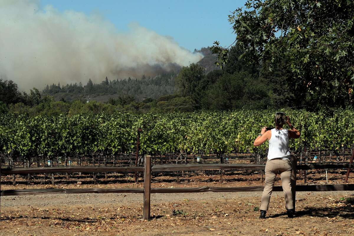 Carol Ort stops on White Cottage Road to photograph the smoke plume as the Glass fire burned north of St. Helena, Calif., on Sunday, September 27, 2020.