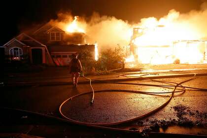A firefighter watches as two houses burn on Mountain Hawk Drive in the Skyhawk area of Santa Rosa.