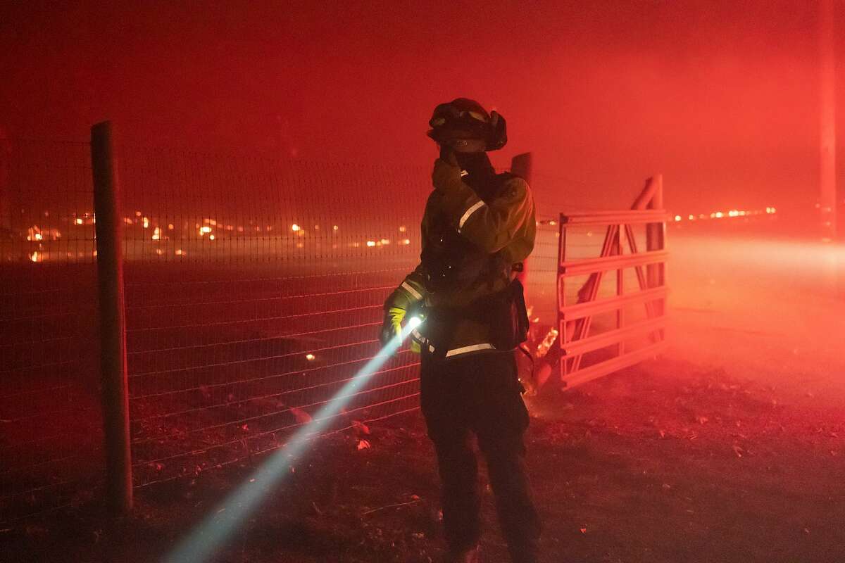 A firefighter looks over a fire threatening a house during the Glass on Monday, Sept. 28, 2020 in Santa Rosa, Calif.