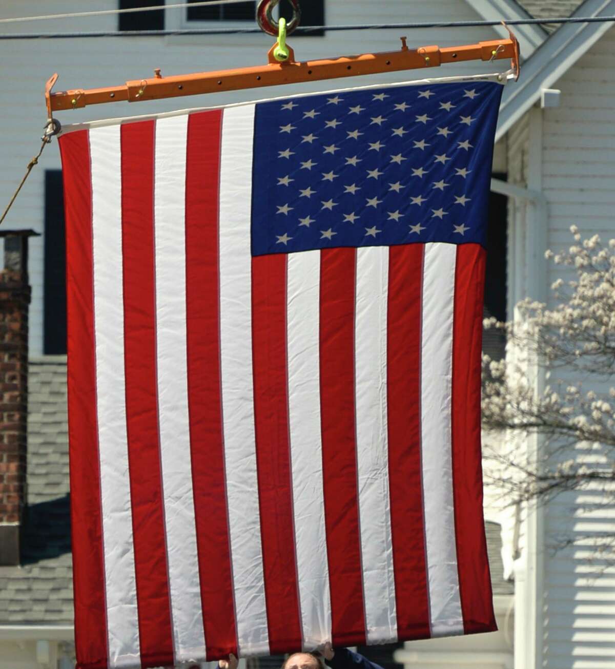 Sue Alves, of Danbury, helps hang an American flag for first responders to drive under as they paraded past the entrance to New Milford Hospital to thank them for their work on the front lines fighting the coronavirus. Tuesday, April 28, 2020, in New Milford, Conn.