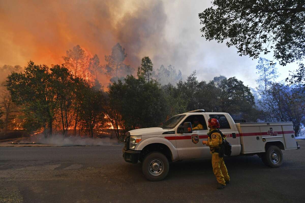 A firefighter glances up as trees begin to catch fire along Crystal Springs Road while battling the Glass Fire in St. Helena, Calif., on Sunday, Sept. 27, 2020.