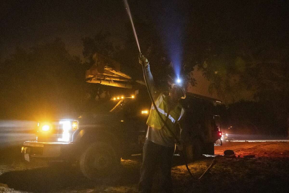 PG&E employee Sean Ohaire hoses down a telephone pole at the Zogg Fire near Igo, Calif., early Monday, Sep. 28, 2020.