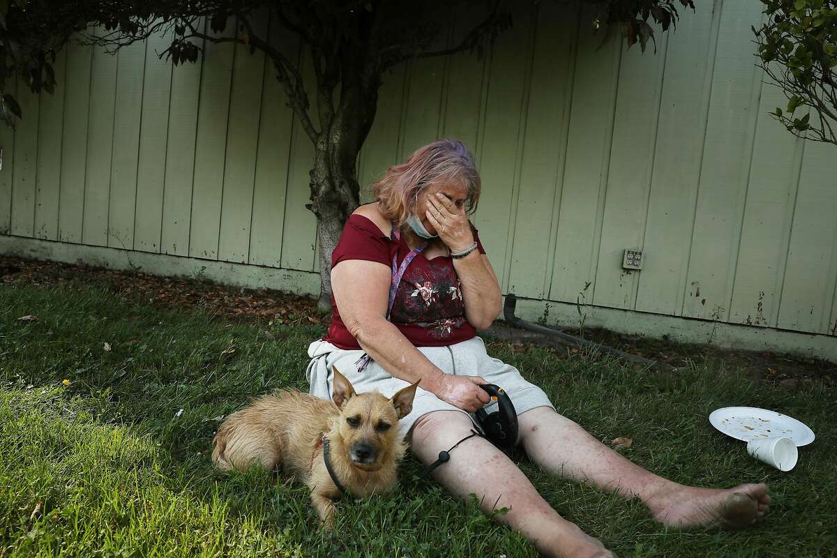 Gloria Young of Santa Rosa cries as she sits with her dog at the Sonoma-Marin Fairgrounds and Event Center after evacuating in the middle of the night from her motor home.