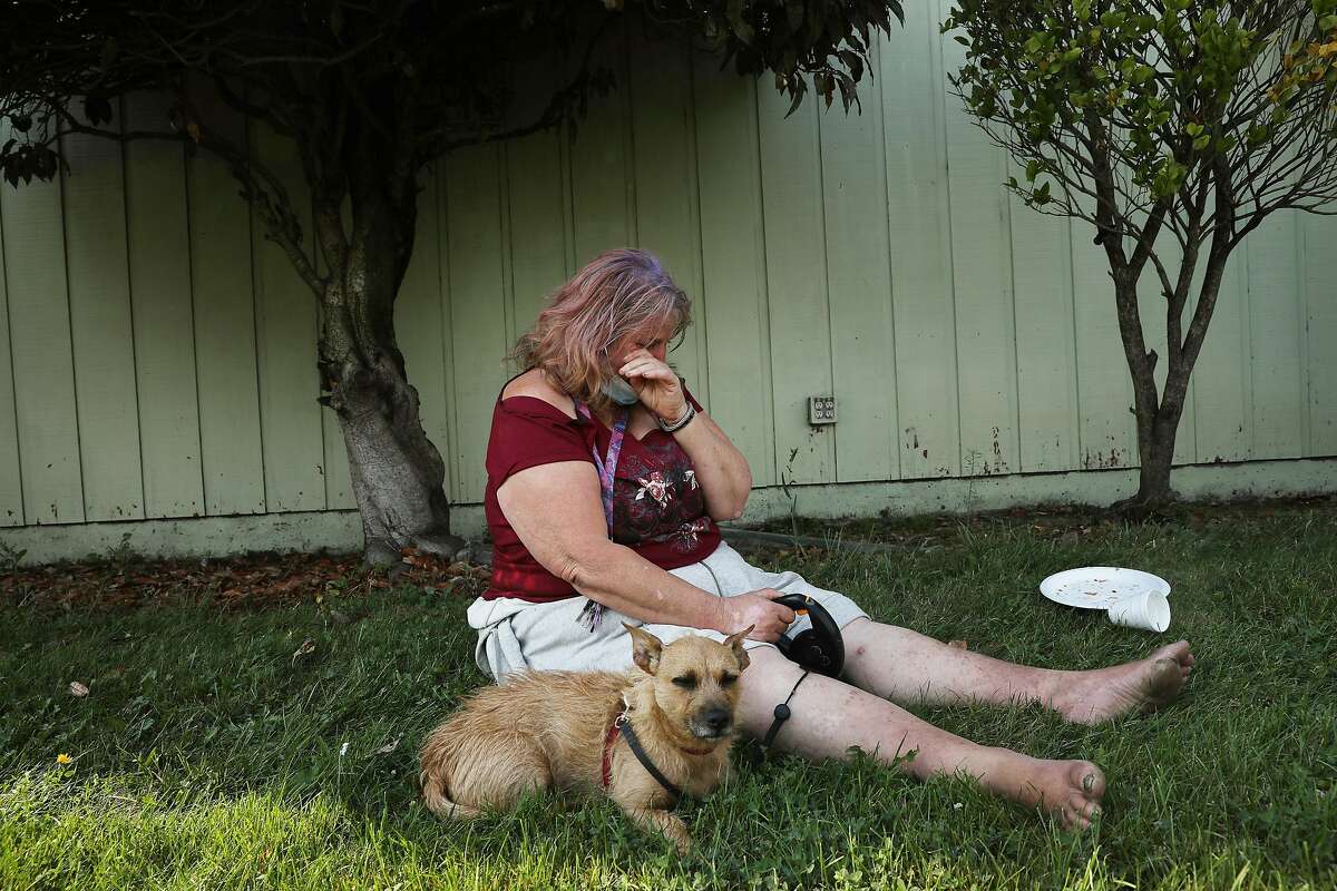 Gloria Young of Santa Rosa wipes tears from her face as she cries as she sits on a patch of grass at the Sonoma Marin Fairgrounds and Event Center after evacuating in the middle of the night from her motor home on Monday, September 28, 2020 in Petaluma, Calif. Young was unsure of the status of her motor home and was waiting to find out from her son who was planning to check on it.