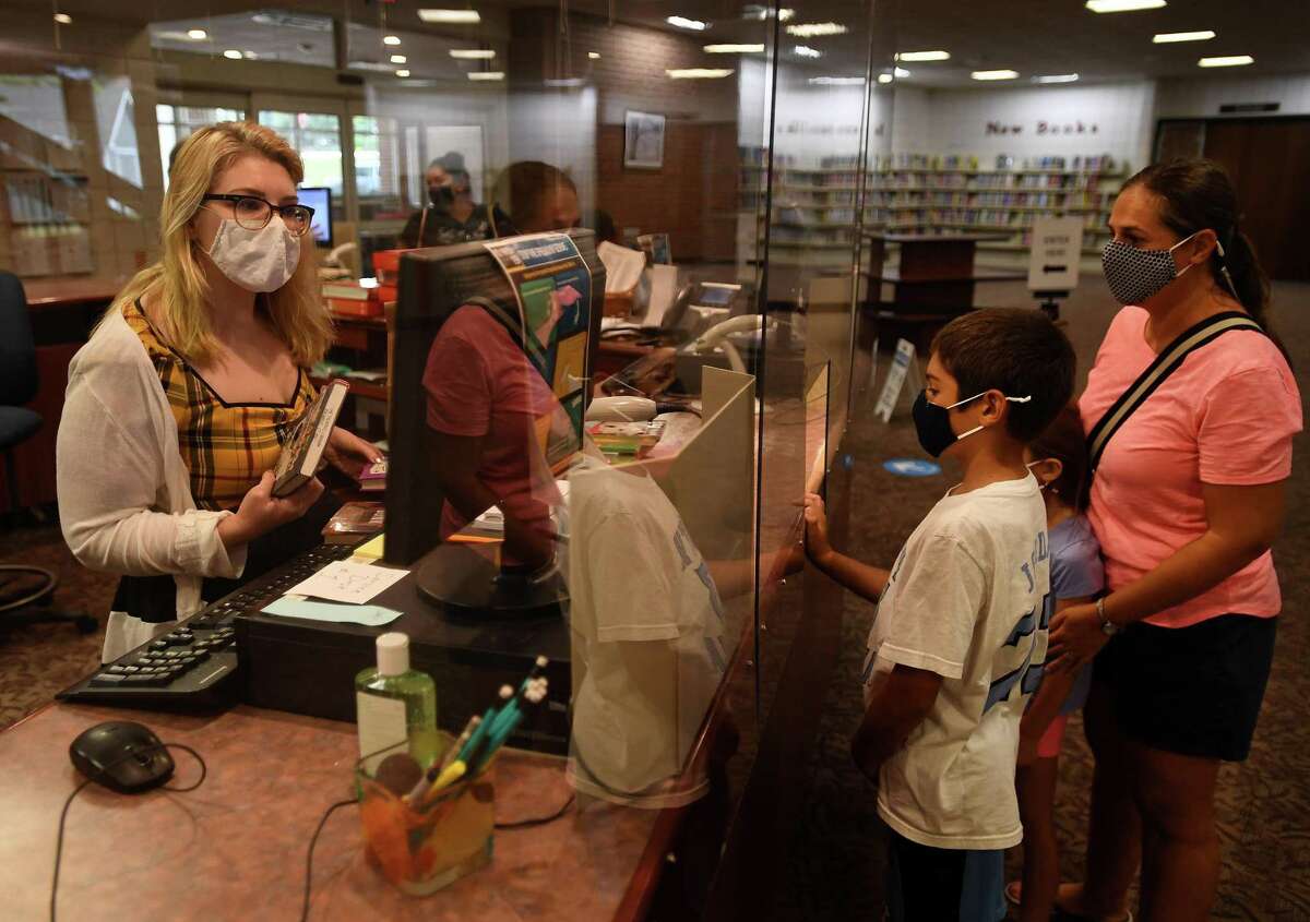 Emily Boyle, son Matthew, 10, and daughter Catherine, 7, check out books on the first day of reopening at the Trumbull Library in Trumbull, Conn. on Monday, September 28, 2020.