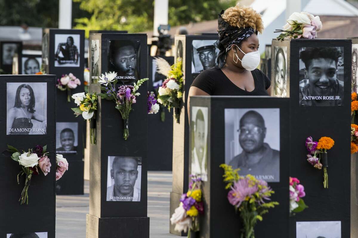 People walk through the Say Their Names Memorial in Emancipation Park on Monday, Sept. 28, 2020 in Houston. Brought to Houston by rap artist and activist Trae Tha Truth and Say Their Names, the memorial is dedicated to those who have lost their lives due to racial injustice. More than 200 photos, including George Floyd, Breonna Taylor, Dr. Martin Luther King, Jr., and Emmett Till to name a few, are featured in the walk of black pillars with photos on each side. The traveling memorial will be installed at the park for 15 days.