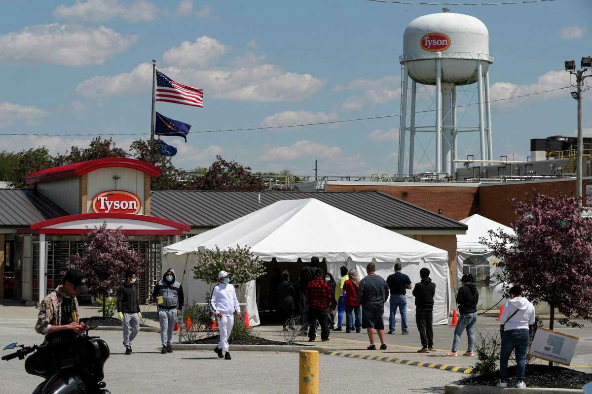 Workers line up to enter the Tyson Foods pork processing plant in Logansport, Ind., Thursday, May 7, 2020. In Cass County, home to the Tyson plant, confirmed coronavirus cases have surpassed 1,500. That’s given the county — home to about 38,000 residents — one of the nation’s highest per-capita infection rates. (AP Photo/Michael Conroy)