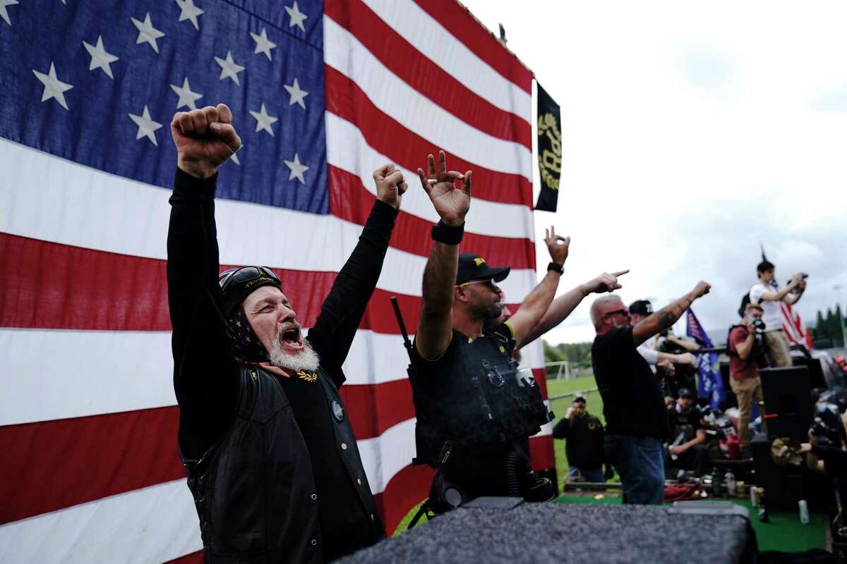 FILE - Members of the Proud Boys cheer on stage as they and other right-wing demonstrators rally, Saturday, Sept. 26, 2020, in Portland, Ore. President Donald Trump didn't condemn white supremacist groups and their role in violence in some American cities this summer. Instead, he said the violence is a “left-wing" problem and he told one far-right extremist group to “stand back and stand by.” His comments Tuesday night were in response to debate moderator Chris Wallace asking if he would condemn white supremacists and militia groups. Trump's exchange with Democrat Joe Biden left the extremist group Proud Boys celebrating what some of its members saw as tacit approval.
