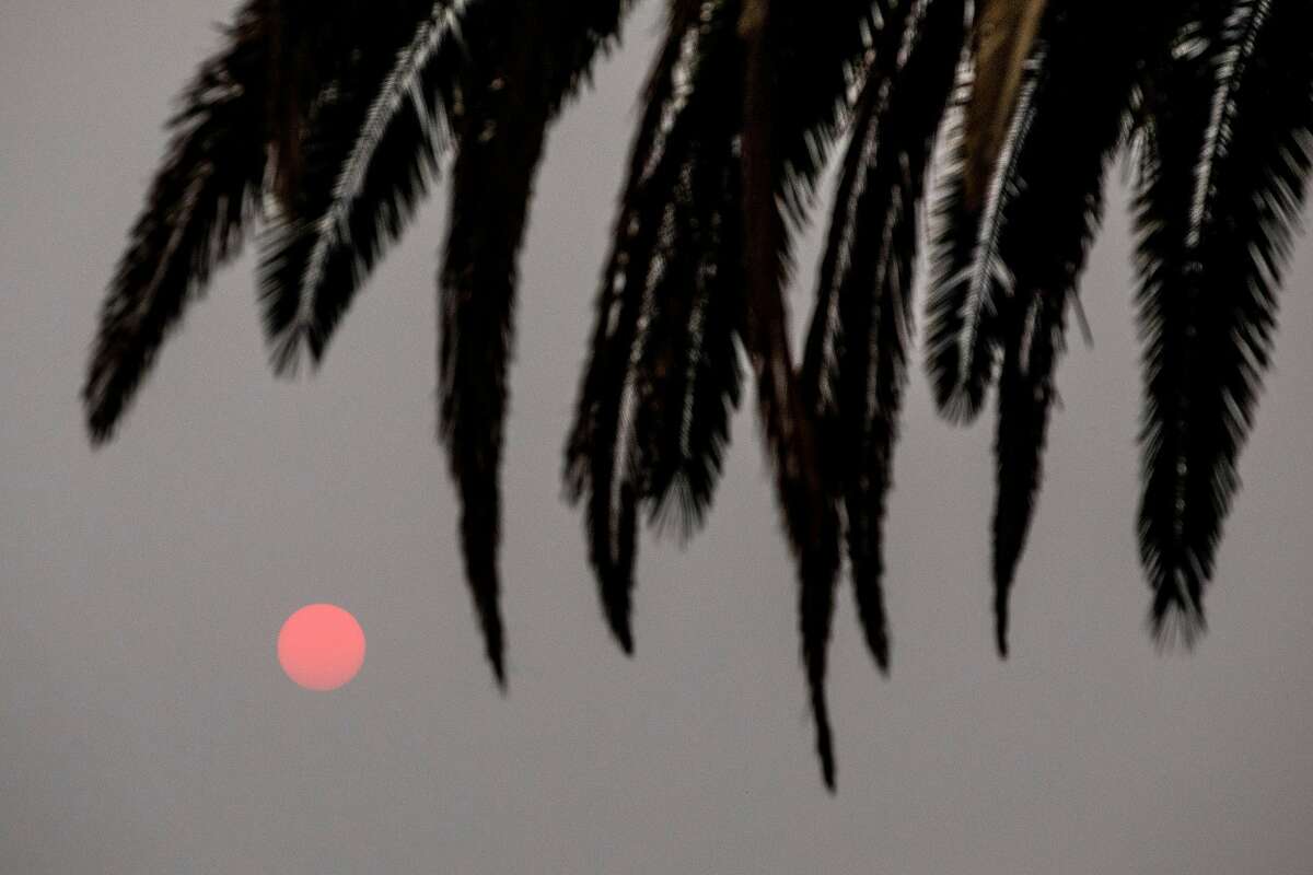 The sun rises as a red ball as the Glass Fire burns behind vineyards east of Silverado Trail in Calistoga on Tuesday.