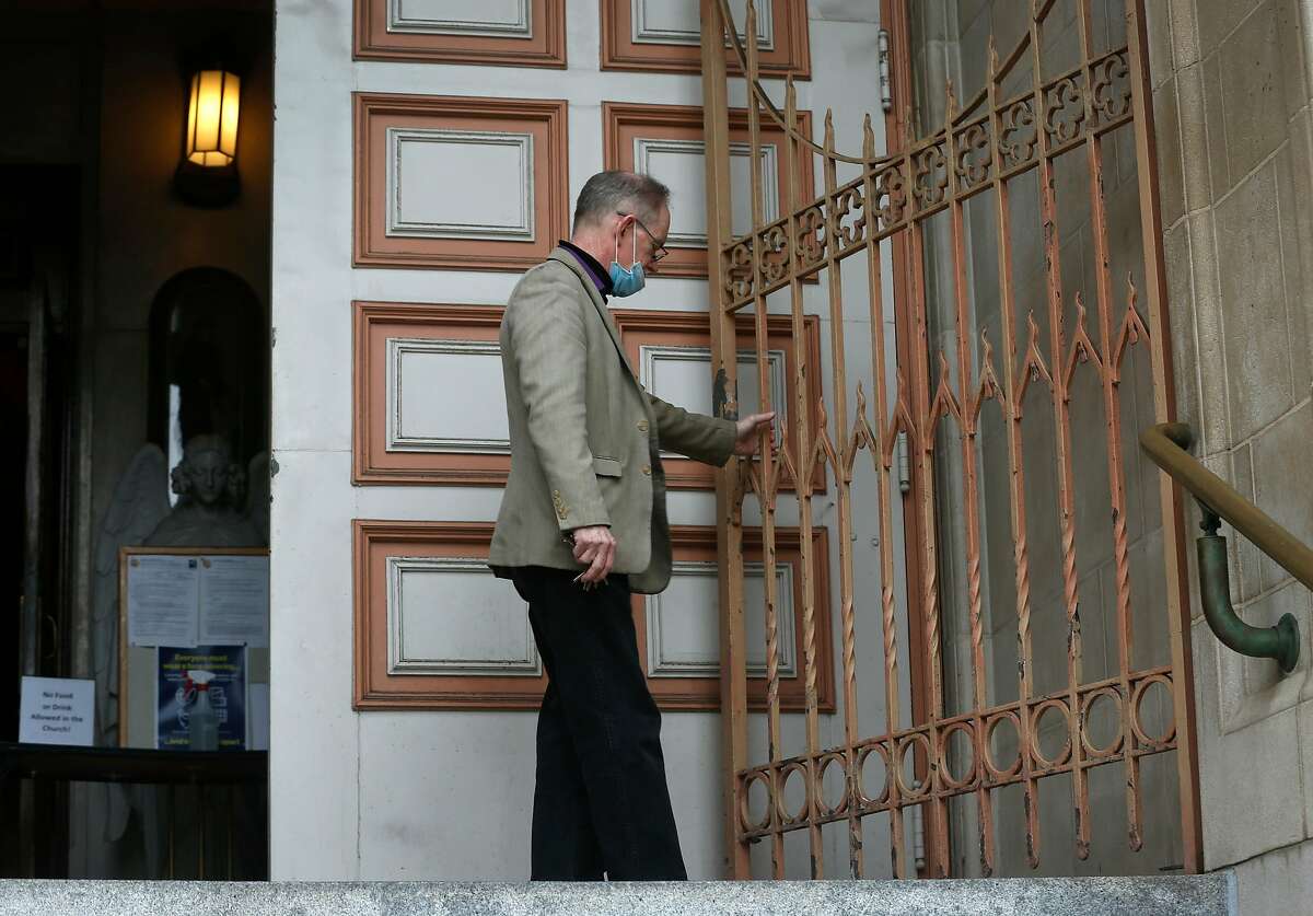 Gibbons Cooney unlocks the gate for the 9 a.m. Mass Wednesday at Sts. Peter and Paul Church in San Francisco.