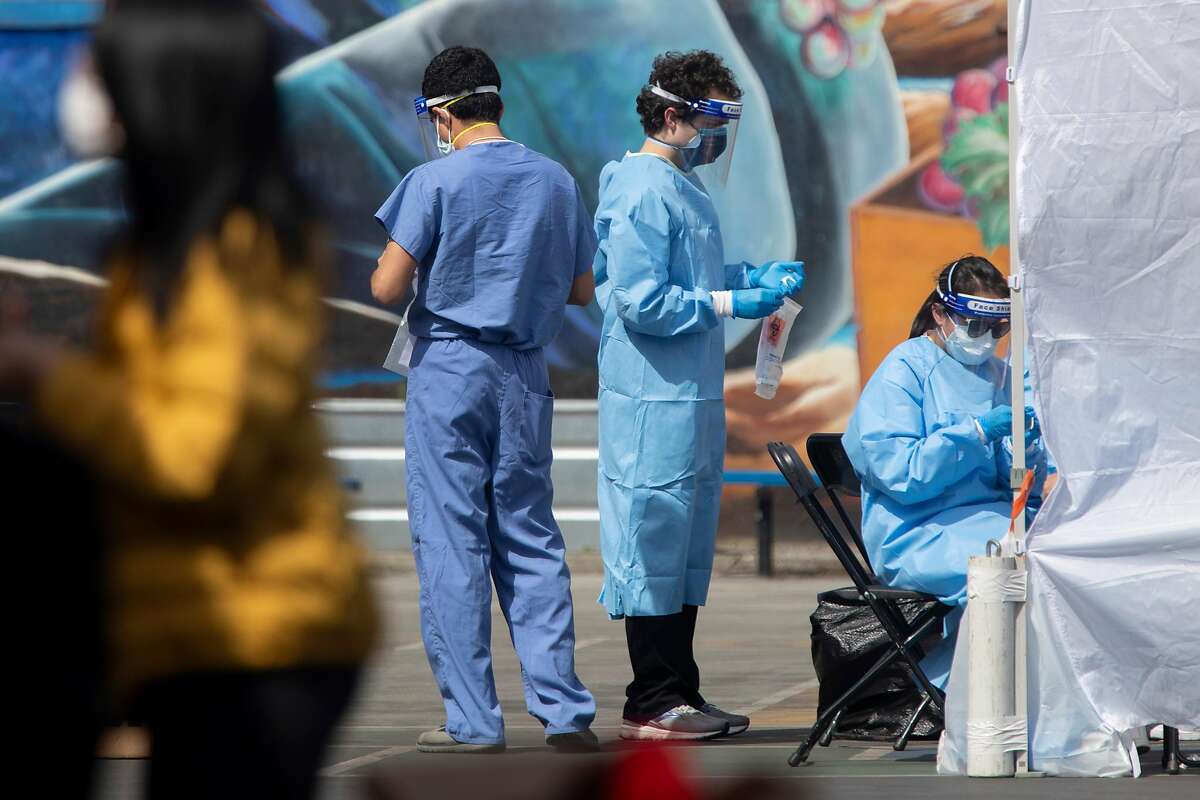 Volunteers and staff with UCSF move people through a coronavirus testing site in the Mission District.