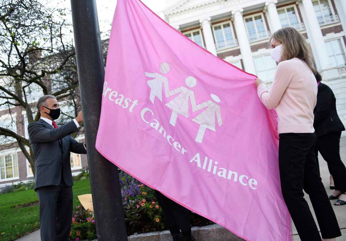 First Selectman Fred Camillo and Breast Cancer Alliance President Meg Russell raise a flag at Town Hall in Greenwich, Conn. Thursday, Oct. 1, 2020. The Greenwich-based non-profit raised a flag with First Selectman Camillo on the first day of Breast Cancer Awareness Month. BCA's fashion show fundraiser will be held virtually this year.