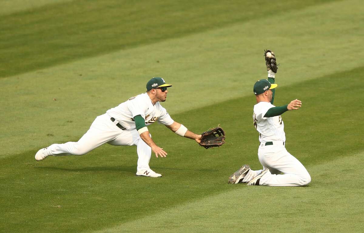 Tommy La Stella, right, of the Oakland Athletics makes a great catch on a ball hit by Adam Engel of the Chicago White Sox as Ramon Laureano watches him in the fifth inning of Game 3 of the American League wild card series at RingCentral Coliseum.
