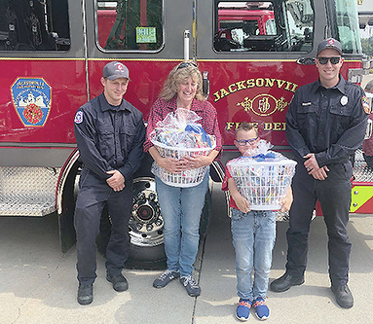 Jacksonville Fire Department members accept gift baskets presented by Buchheit retail department manager Sue Radkiewicz and her grandson, Jackson.