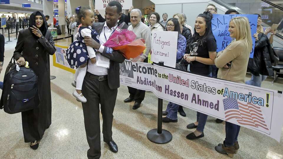 FILE - This Feb. 10, 2017, file photo, Abdisellam Hassen Ahmed, a Somali refugee who had been stuck in limbo after President Donald Trump temporarily banned refugee entries, walks with his wife Nimo Hashi, and his 2-year-old daughter, Taslim, who he met for the first time after arriving at Salt Lake City International Airport. Refugee advocates, including faith-based groups that President Donald Trump is courting in his re-election bid, called on Congress Thursday, Oct. 1, 2020, to halt his administration’s plans to slash the limit on refugees allowed into the U.S. to a record low, saying it goes against America’s values. (AP Photo/Rick Bowmer, File)