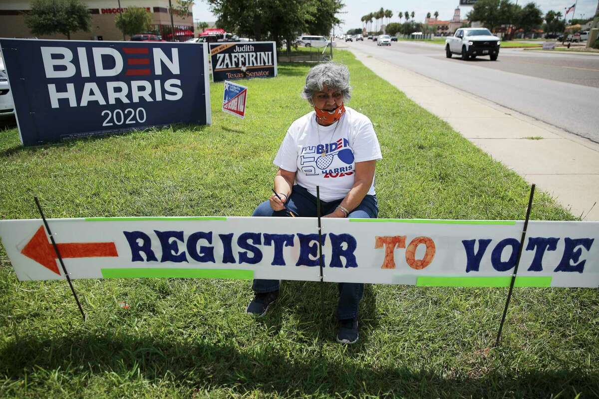 Dora Gonzalez takes a pause in touching up a sign to encourage people to register to vote at the Webb County Democratic Party headquarters in Laredo on Wednesday, Sept. 23, 2020.