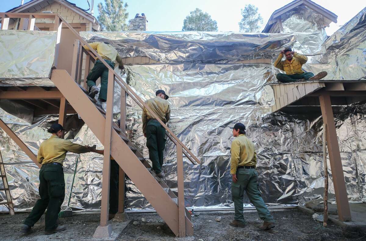 Bear Divide Hotshots firefighters apply structure wrap to a ranger station to protect it from the Bobcat Fire on Sept. 19, 2020, in Wrightwood, Calif. A similar structure wrap was used in Sequoia National Park to protect a historic ranger station from the flames of the SQF Complex.