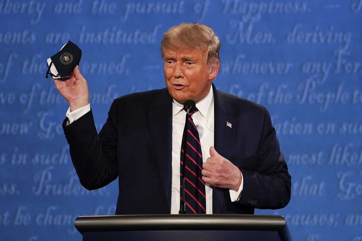 President Donald Trump holds up his face mask during the first presidential debate at Case Western University and Cleveland Clinic, Sept. 29, 2020.