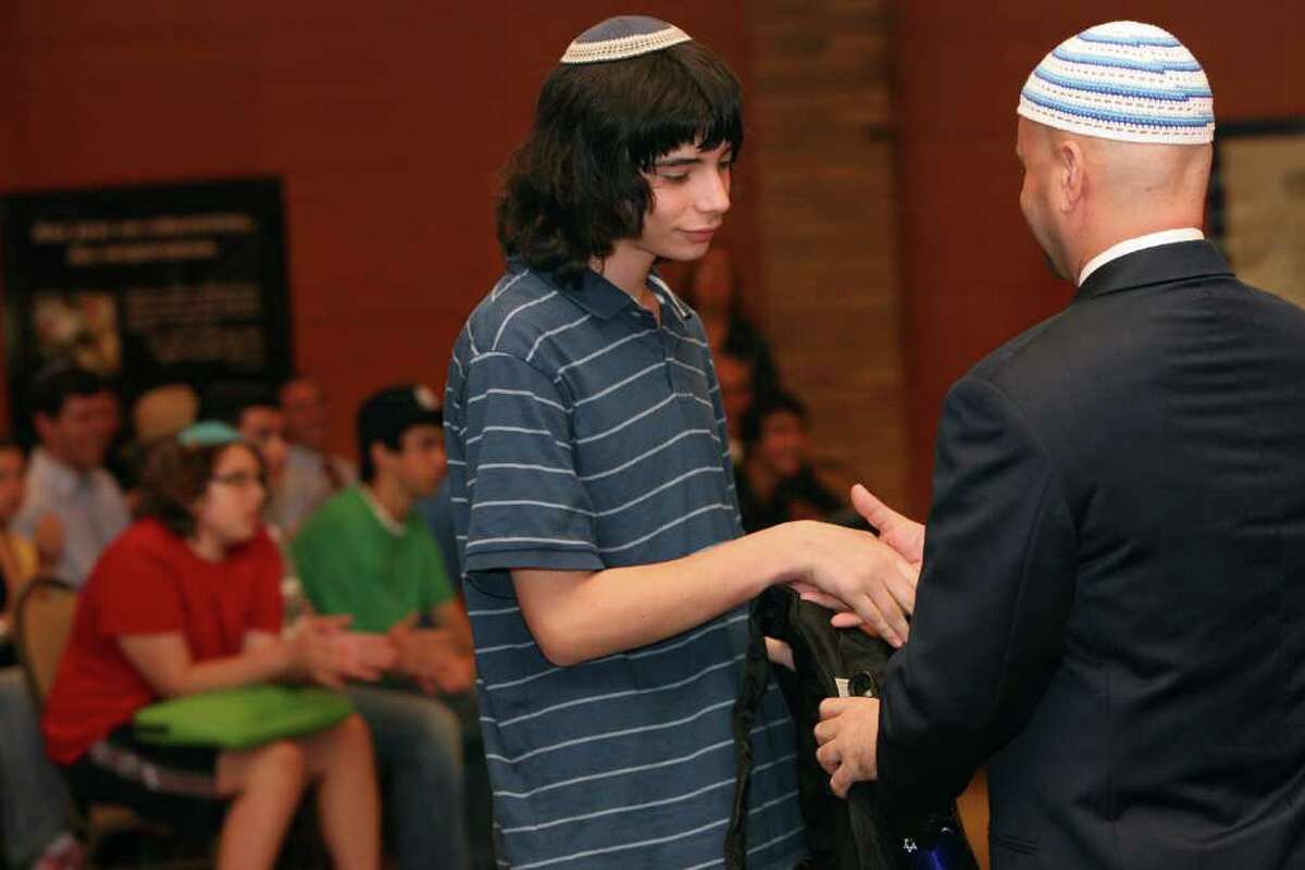 Student Zev Feller, of Stamford, receives a welcome gift at the dedication of the Jewish High School of Connecticut in Bridgeport on Monday, August 30, 2010.