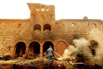 Above: Cellar worker Jose Juan Perez sprays water on burning debris at Castello di Amorosa in Calistoga, which was damaged in the Glass Fire last week.
