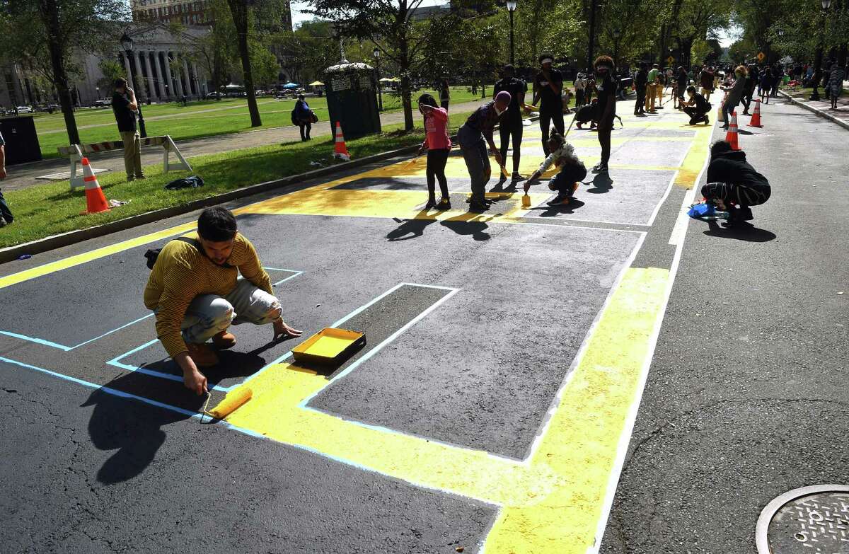 Volunteers paint a Black Lives Matter mural on Temple Street next to the New Haven Green on October 3, 2020. Jesse Wolfe, one of the artists that designed the mural, said it was important for him to do something to remember the Black lives that have been lost in encounters with police. “Hopefully this is a reminder to police, when they drive by, just take heed and remember that Black lives do matter and take a little more caution, instead of pulling out guns and killing us,” he said. He said recently he was profiled when walking on Whalley Avenue in New Haven. “He (a police officer) pulled a gun on me. All I had in my hand was my mask. He apologized because I wasn’t the person.” Wolfe said. “The description didn’t even describe me. I was a little messed up after that. That’s why I am proud to be a part of this.”