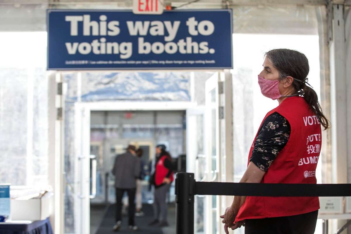 Jenny Stanley guides people to voting booths on the first day of early, in-person voting outside of the Bill Graham Civic Auditorium in San Francisco on Monday.