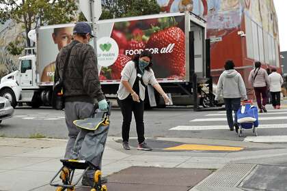 SF-Marin Food Bank senior program manager Tina Gonzales helps maintain social distancing as the food bank hands out 1,600 food bags at a pop-up pantry at Bayview Opera House in San Francisco in April. Food bank workers recently ratified their new union contract.