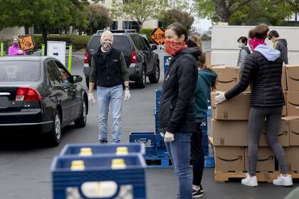 SF-Marin Food Bank executive director Paul Ash assists volunteers during a drive-through food bank pick-up in San Rafael in April.