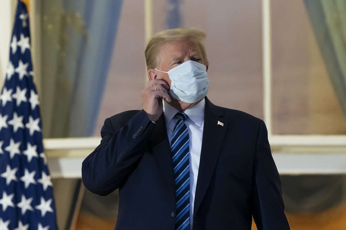 President Trump removes his mask Monday on the Blue Room Balcony upon returning to the White House from Walter Reed Medical Center.