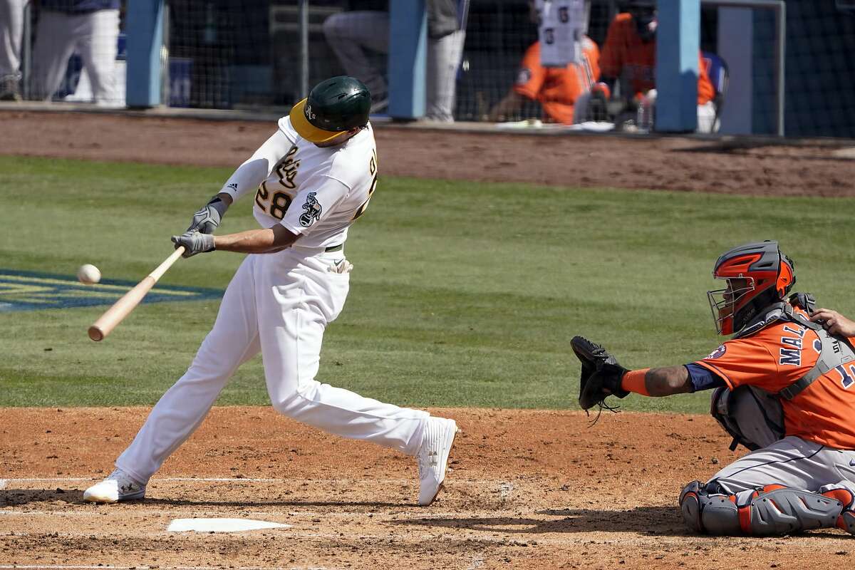 Oakland Athletics' Matt Olson (28) hits a solo home run in front of Houston Astros catcher Martin Maldonado during the fourth inning of Game 1 of a baseball American League Division Series in Los Angeles, Monday, Oct. 5, 2020. (AP Photo/Marcio Jose Sanchez)