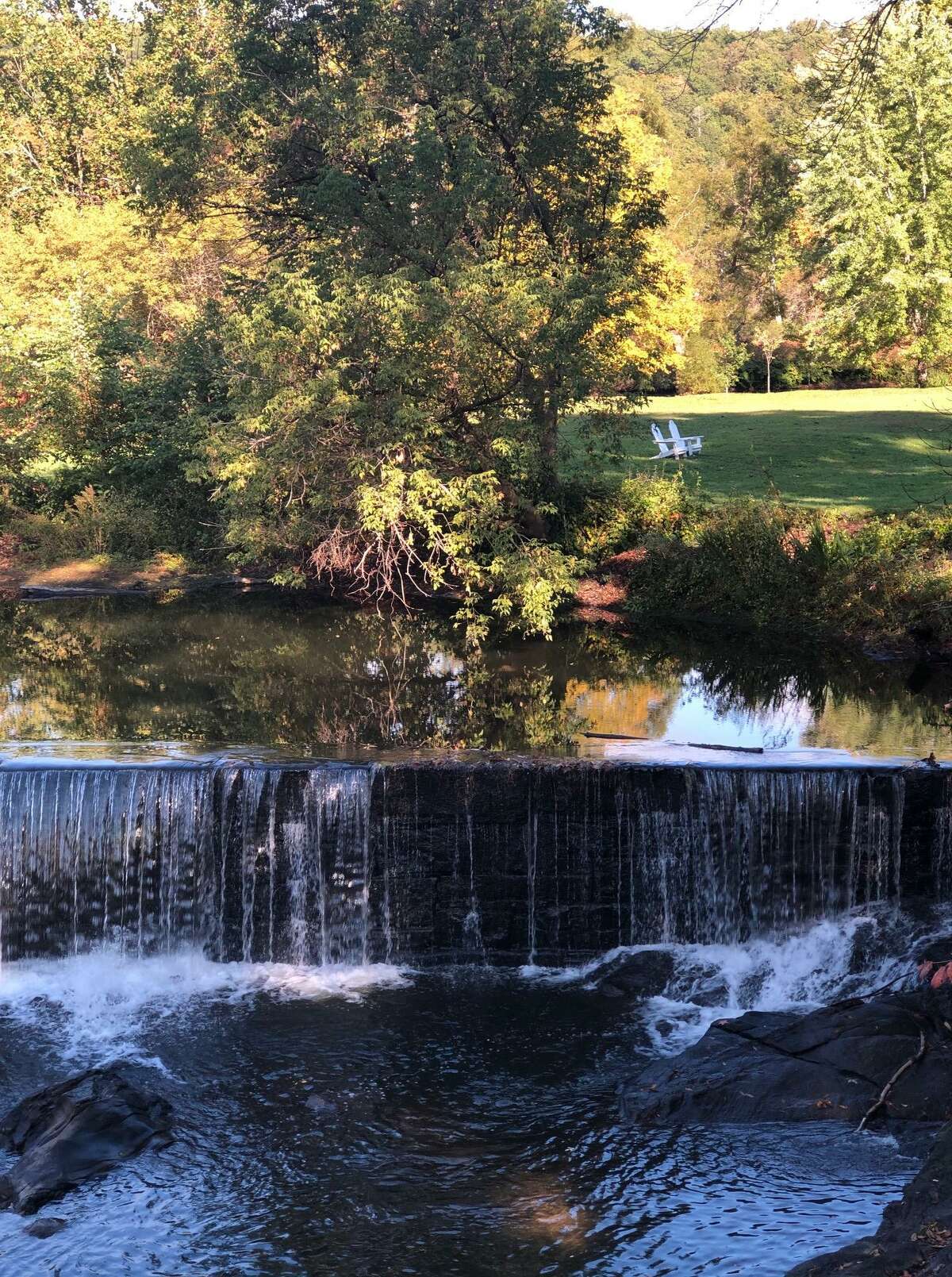 The quiet Shepaug River near Mine Hill casts a contrasting image against a field with two lone chairs in the background.