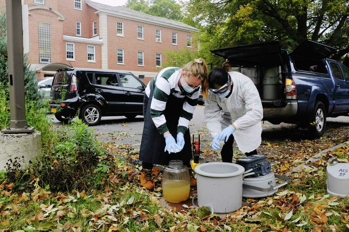 Siena College Environmental Studies students, junior Cassidy Hammecker, left, and senior Jennifer Guzman collect wastewater outside a dorm on Tuesday, Oct. 6, 2020, in Loudonville, N.Y. Monitoring systems that measure COVID-19 in wastewater have cropped up on the state, municipal and college levels in New York. (Paul Buckowski/Times Union)
