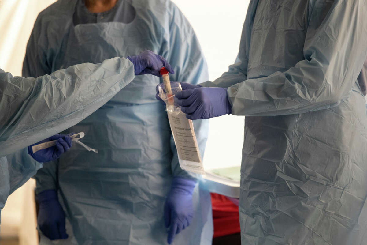 SEATTLE, WASHINGTON - MARCH 13: Nurses wearing protective clothing handle a vial containing a potentially infected coronavirus swab at a drive-through testing center at the University of Washington Medical campus on March 13, 2020 in Seattle, Washington.