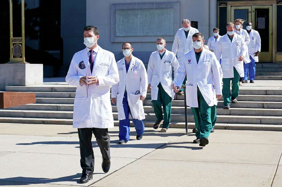 Dr. Sean Conley, physician to President Donald Trump, is followed by a team of doctors for a briefing with reporters Saturday at Walter Reed National Military Medical Center, where Trump was admitted after contracting the coronavirus.