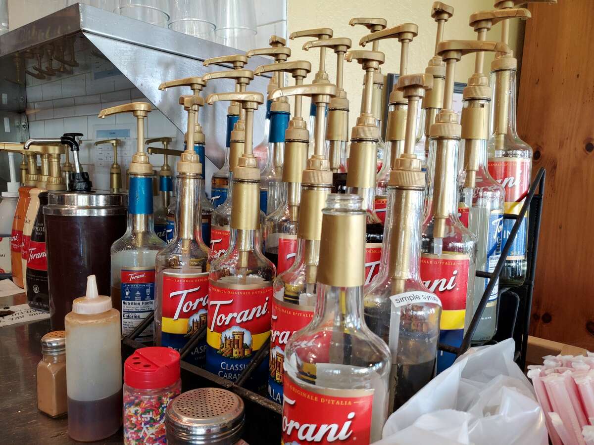Close-up of rows of Torani syrups, used to flavor Italian sodas or other beverages, in a coffee shop.