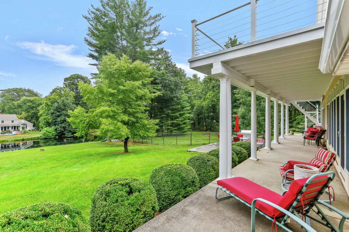 The house sits on a one-acre level and gently sloping property looking over the Saugatuck River. Throughout the house there is an alluring mix of materials. Each one stands out on its own, yet it also dovetails seamlessly into the other, like a luxurious jigsaw puzzle to create the whole attractive image. In the spacious great room there is cherry wood flooring and the light tone of the custom-designed, built-in, quarter-sawn Anigre wood cabinetry - an African hardwood, juxtaposed against the honed, stacked granite of the wide, floor-to-ceiling dual-sided fireplace. The other side of this hand-crafted, wood-burning fireplace opens into the dining area of the gourmet kitchen, which features a polished granite floor, center island/breakfast bar, marble counters and high-end stainless appliances including a large Sub-Zero refrigerator/freezer. The dining area has a door to the porch and patio, as well as stairs to the balcony with cedar wood decking that can also be accessed from the second floor master bedroom suite.