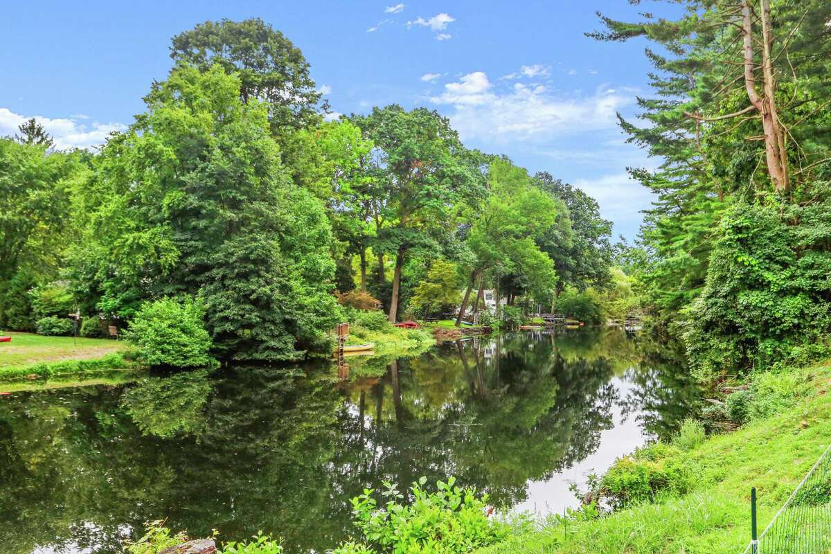 Watch swans glide by or paddle down the Saugatuck River from this backyard. The floating staircase to the second floor has a polished stainless steel railing. On the second floor, the cavernous master suite has a vaulted ceiling, sitting area, walk-in closet, and a large private bath with a double-sided steam shower. This suite is so large that one section could be annexed to expand the luxury even further by adding a jetted or soaking tub. Imagine relaxing while taking in river views. On the second floor there is one other room that could be an ideal office, study, homework station, or art studio. All of the updated bathrooms feature marble flooring in a basket-weave pattern, glass tile backsplash and glass sinks. On the partial, partially finished walk-out lower level there is a laundry area with a utility sink, workshop area and a wealth of storage space.