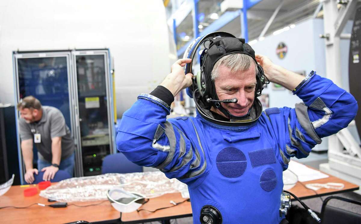 Astronaut Chris Ferguson adjusts his helmet as he trains for flight in a Starliner mock-up at NASA's Johnson Space Center.