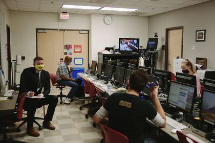 Student Anchor Ryan Ketcham (left to right) goes over notes as Professor Ben Davis speaks to Student Video Coordinating Producer Bryce Wayne and Student Producer Emily Brubaker inside the newsroom before recording an episode of the Valley View News show in their television news class on campus at CSU Northridge in Northridge, California September 28, 2020. Due to the pandemic, students must wear masks (except the anchors when the show is recording), keep distances when possible, and wipe down their stations for safety.