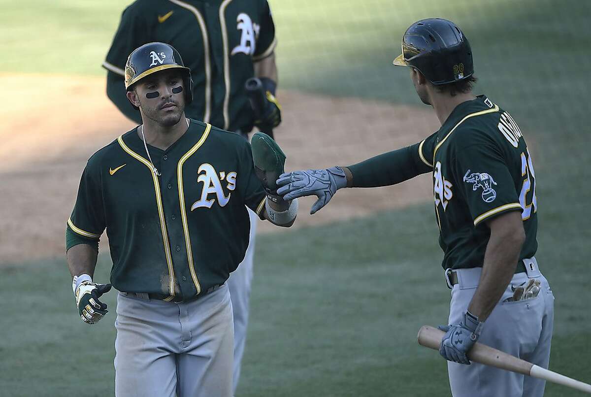 Ramon Laureano #22 of the Oakland Athletics is congratulated by Matt Olson #28 after scoring a run on a sacrifice fly by Chad Pinder #18 during the eighth inning in Game Three of the American League Division Series against the Houston Astros at Dodger Stadium on October 07, 2020 in Los Angeles, California.